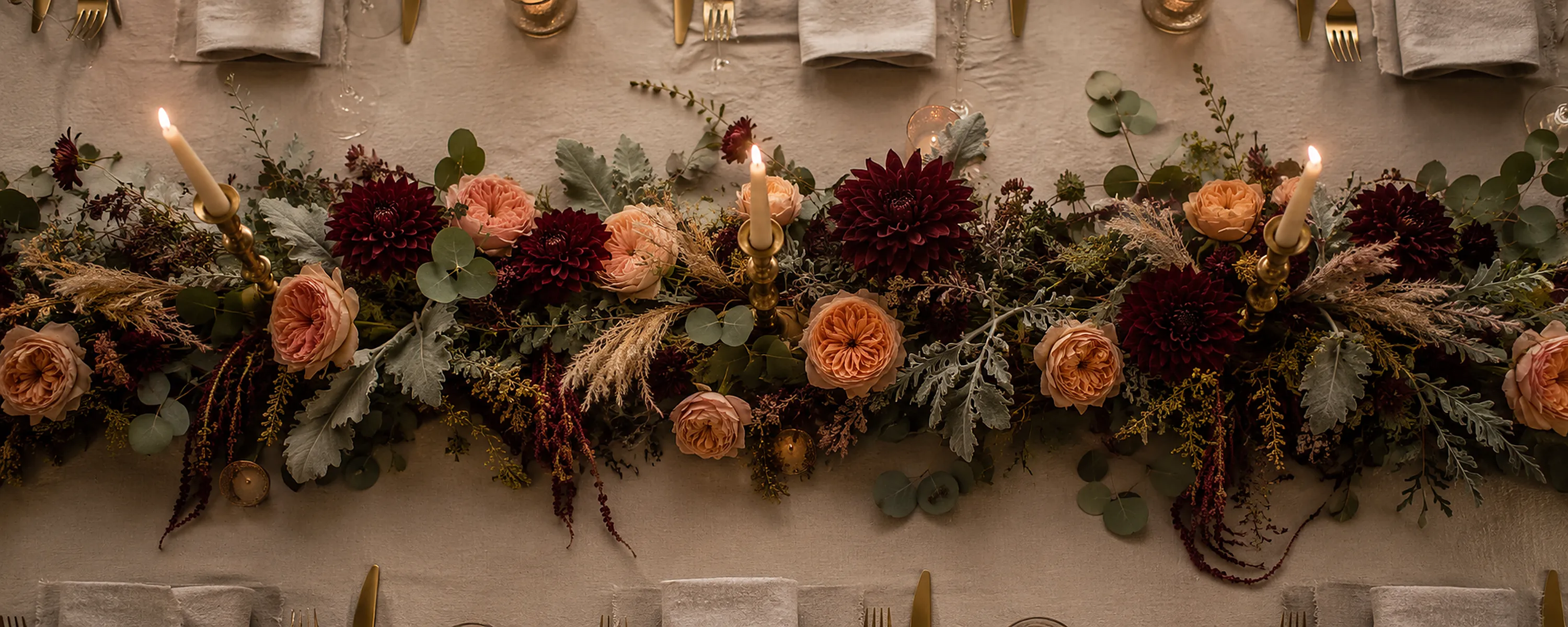 An overhead view of a low candlelit table with a floral centrepiece