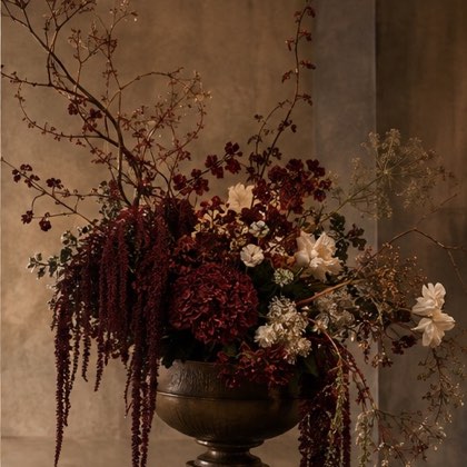 Sculptural burgundy and ivory flowers in an antique urn